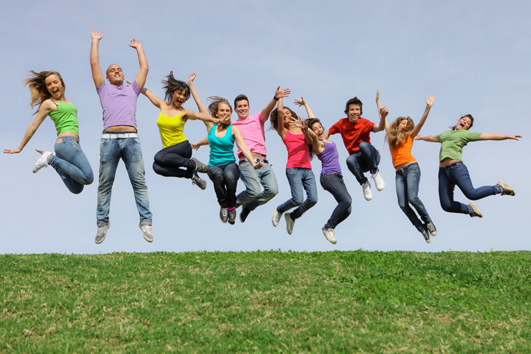 Młodzi ludzie skaczący na polanie - Stock Photo